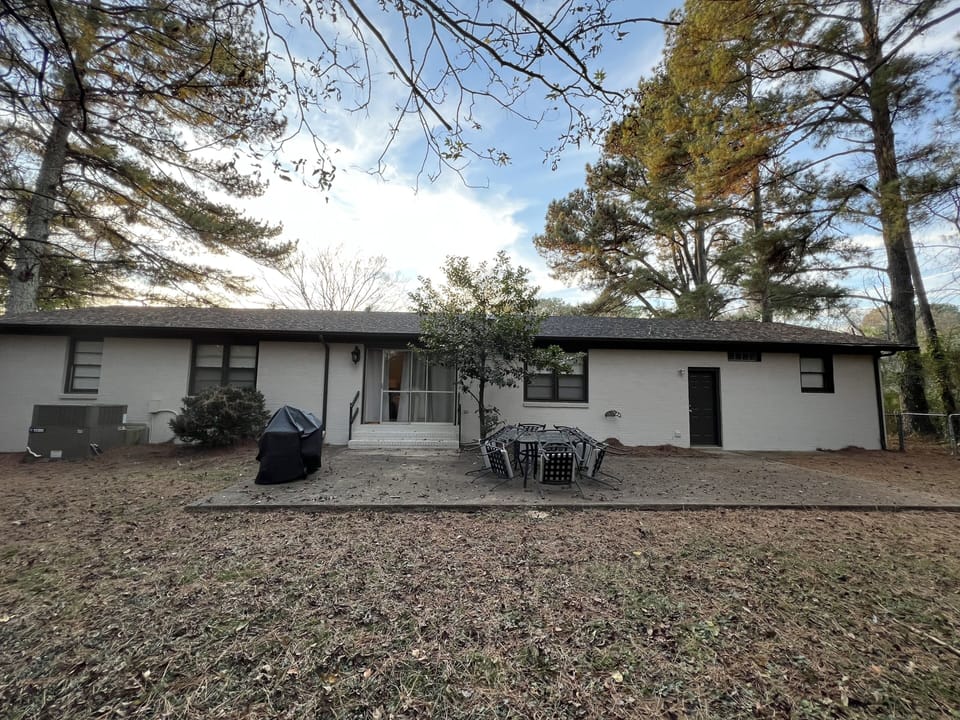 Large fenced in backyard with charcoal grill and seating area