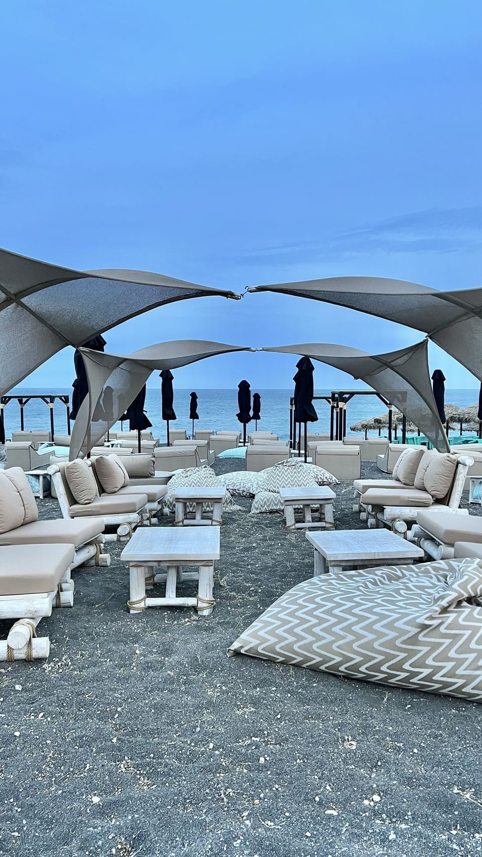 On the beach, black sand, sun loungers, beach umbrellas