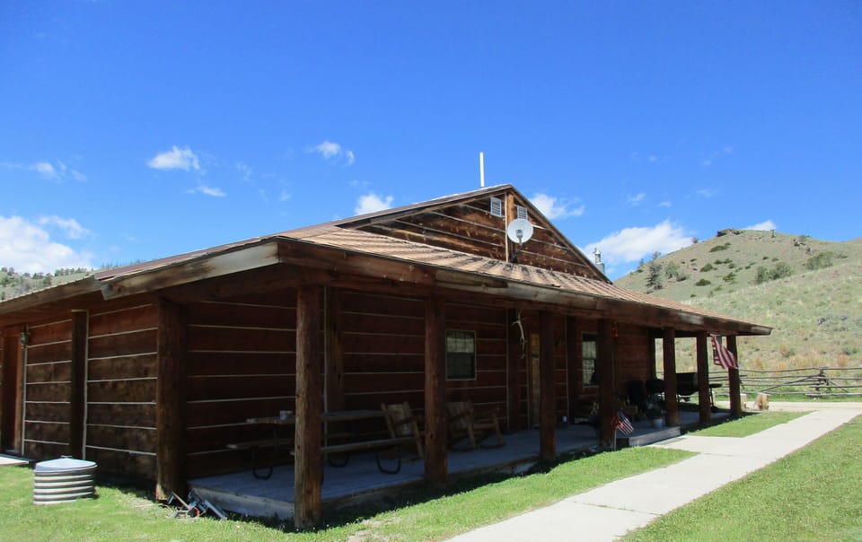 Front porch with picnic table, rockers and BBQ.