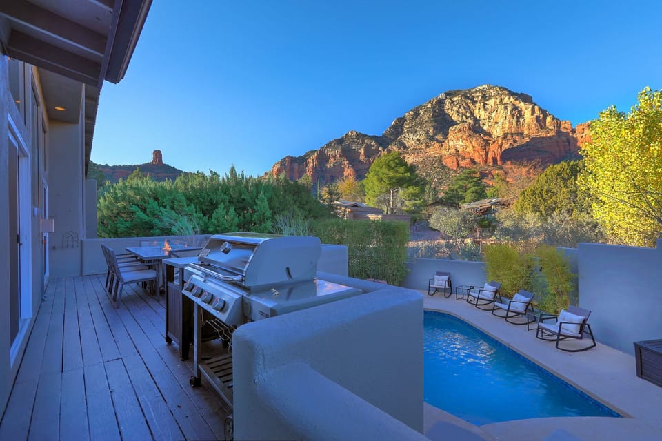 Outdoor patio with dining table and BBQ grill.