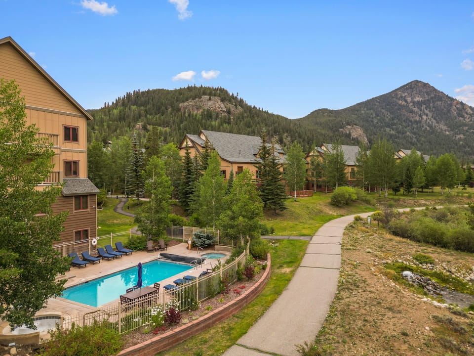 This property features a refreshing pool area surrounded by mountain scenery, with forested peaks and walking paths throughout the peaceful grounds.