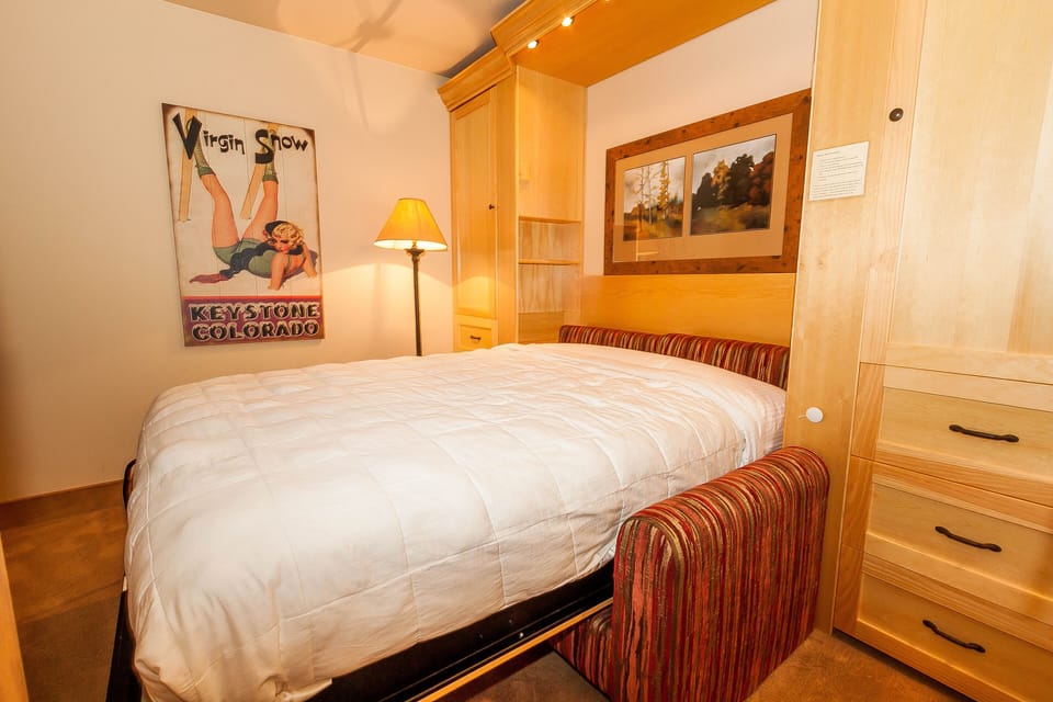 Cozy up in this thoughtfully designed bedroom featuring built-in storage and warm wood finishes that create your perfect mountain retreat sanctuary.