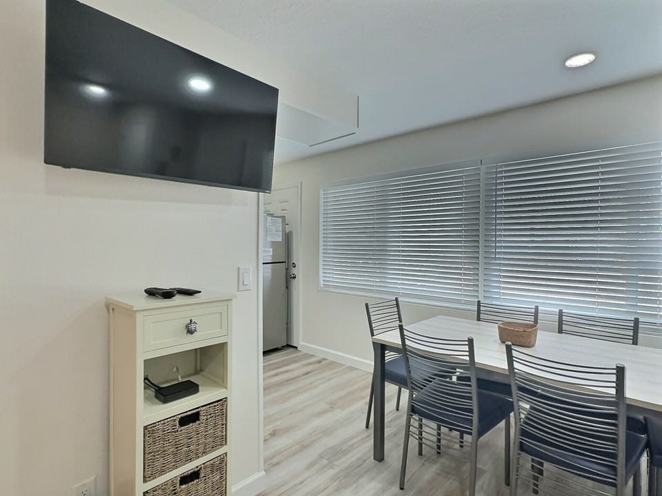 Den with desk, chairs, wall-mounted TV, and plantation shutters