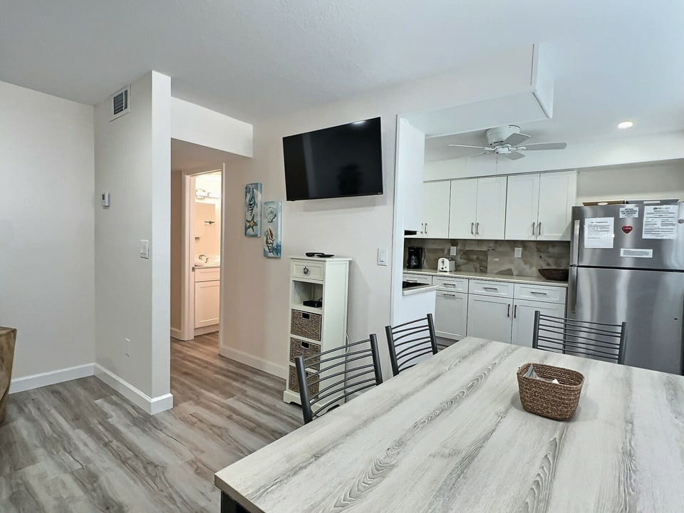 Open floor plan showing living area, mounted TV, and view toward kitchen