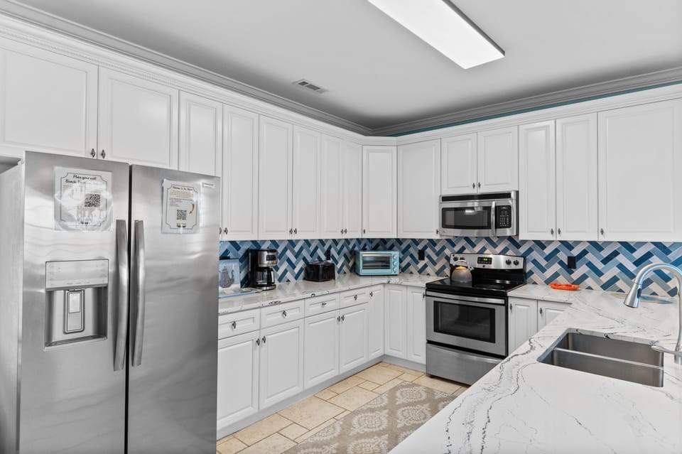 Your fully equipped kitchen features stainless appliances, and a stunning blue chevron backsplash.