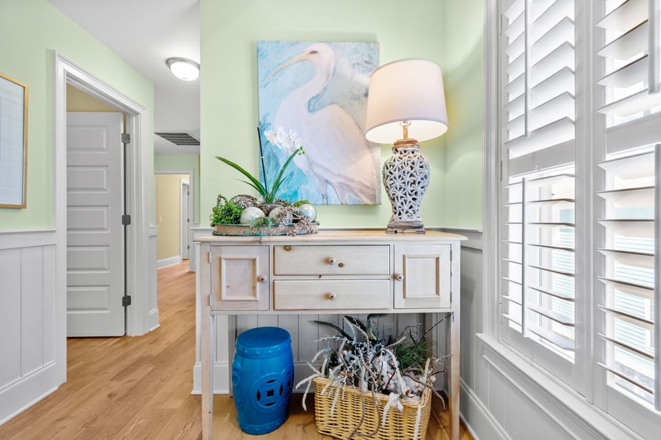 Relax in your beautifully decorated entryway with soft green walls, coastal artwork, and charming furnishings that welcome you home.