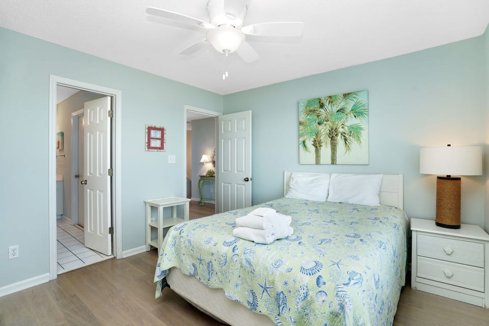 You'll drift off peacefully in this tranquil coastal bedroom with breezy ceiling fan, tropical artwork, and ocean-inspired colors creating your perfect seaside retreat.