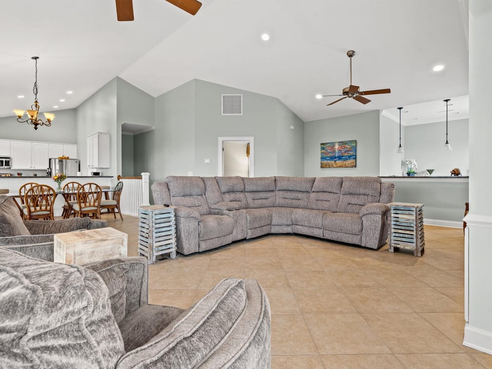 Sink into the plush sectional sofa in this open-concept living space, where vaulted ceilings and coastal charm create your perfect home base.