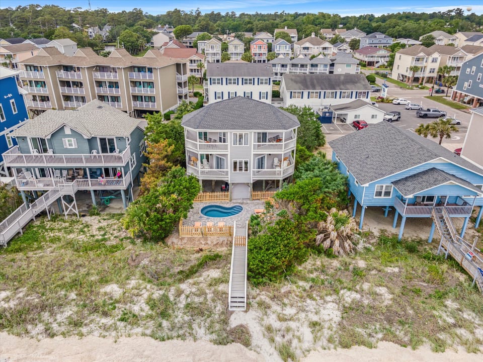 Coastal retreat featuring a private pool, elevated deck, and beachfront access surrounded by charming vacation homes.