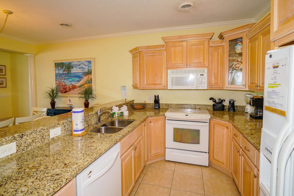 Your fully equipped kitchen features granite counters, modern appliances, and tropical artwork—perfect for preparing vacation meals.