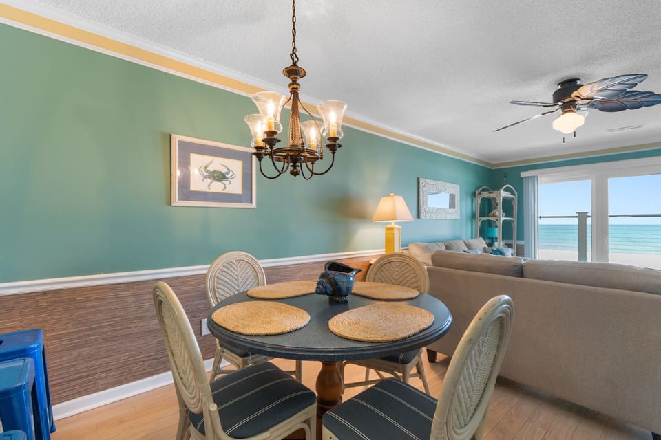 Gather around this inviting dining table with coastal charm, where you can enjoy meals together while the soft sea breeze drifts in from your private balcony overlooking stunning turquoise waters.