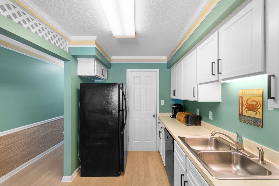 Picture yourself preparing meals in this welcoming kitchen with crisp white cabinets, refreshing teal walls, and everything you need at your fingertips—from coffee maker to full-size appliances.