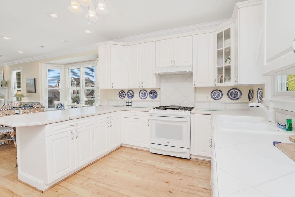 Cook with ease in this bright, spacious kitchen featuring white cabinets, marble countertops, and modern appliances for your culinary adventures.