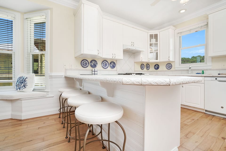 Your bright kitchen awaits with pristine white cabinets, marble counters, and a breakfast bar perfect for morning coffee.