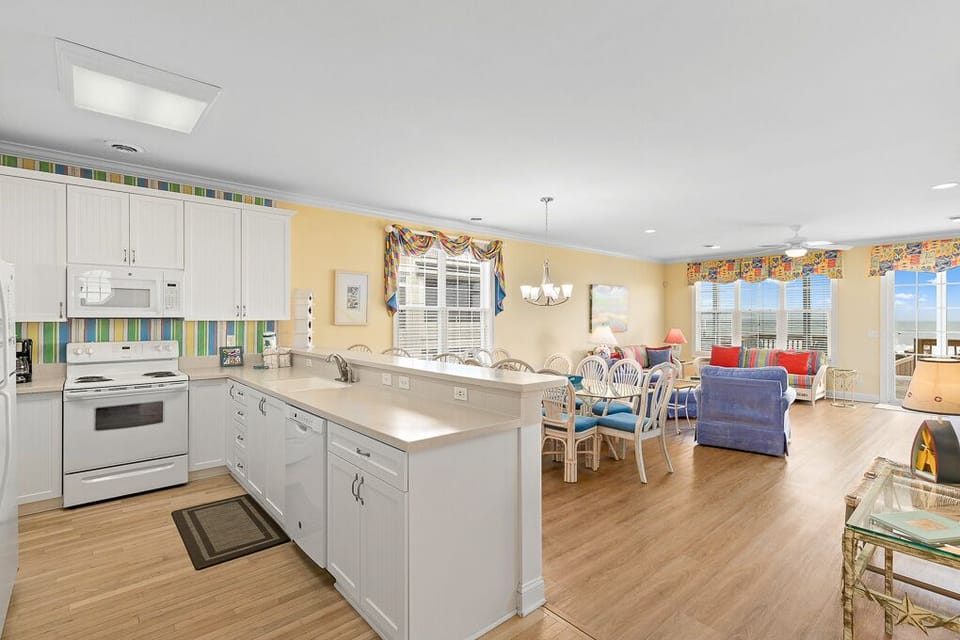 Your spacious open-concept home features gleaming white kitchen with breakfast bar flowing into bright dining and living areas with stunning ocean views.