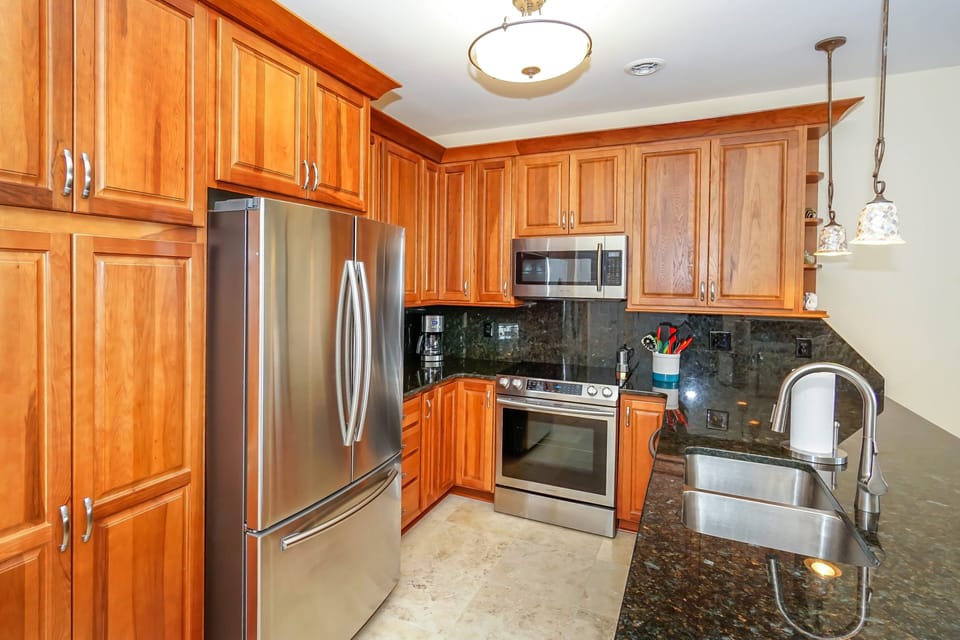 Your fully-equipped kitchen invites culinary adventures with rich wood cabinetry, granite counters, and premium stainless steel appliances for memorable meal prep.