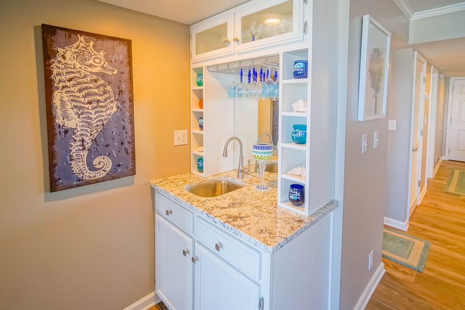 Your wet bar awaits with granite counters, wine glass storage, and coastal charm - perfect for evening cocktails.