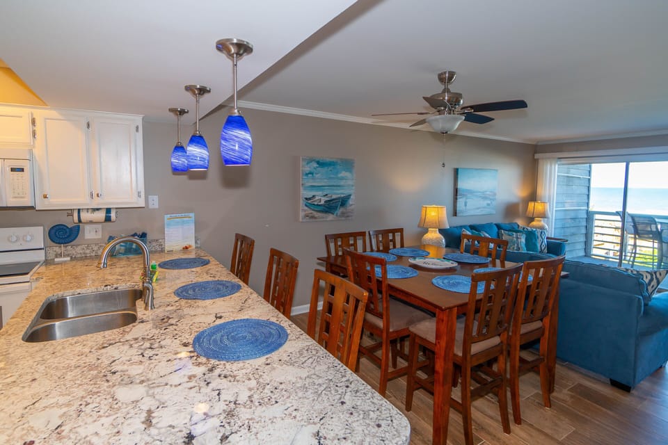 Gather around your spacious kitchen island and dining table, where ocean blues complement granite counters and sea views through sliding doors.