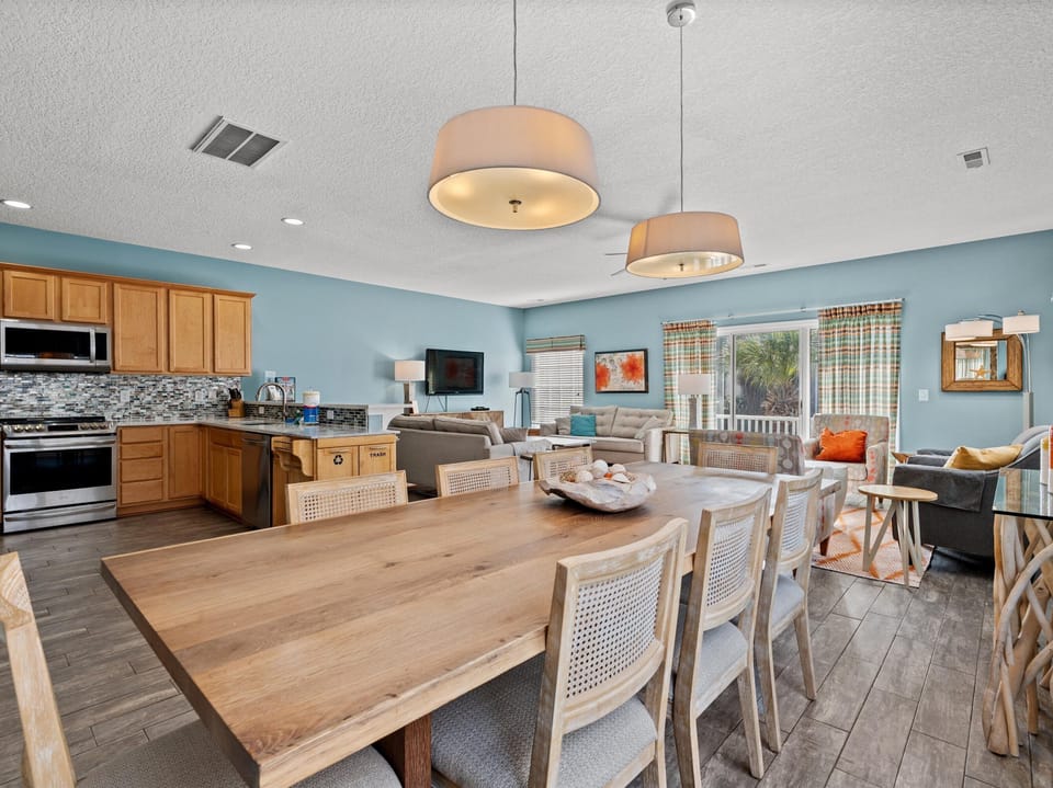 Your spacious open-concept living area blends kitchen, dining, and lounging seamlessly with warm wood accents and soothing coastal colors.