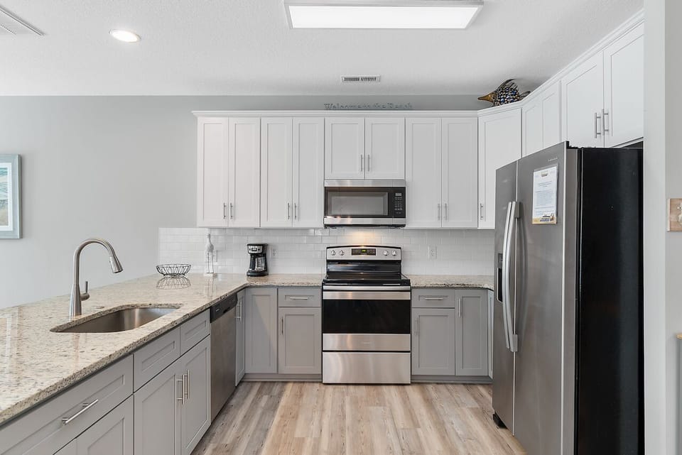 Your fully equipped kitchen features stainless steel appliances, granite countertops, and modern white cabinetry for effortless meal preparation.