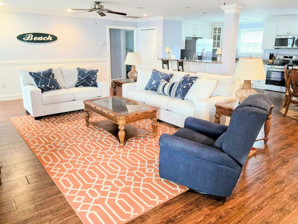 Sink into plush coastal comfort in your spacious living area, where nautical blues meet warm woods and beach vibes welcome you home.