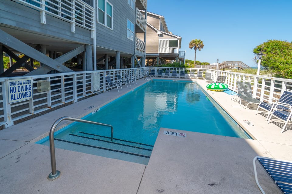 Shared communal pool covered in swaying palms in this peaceful coastal pool area.
