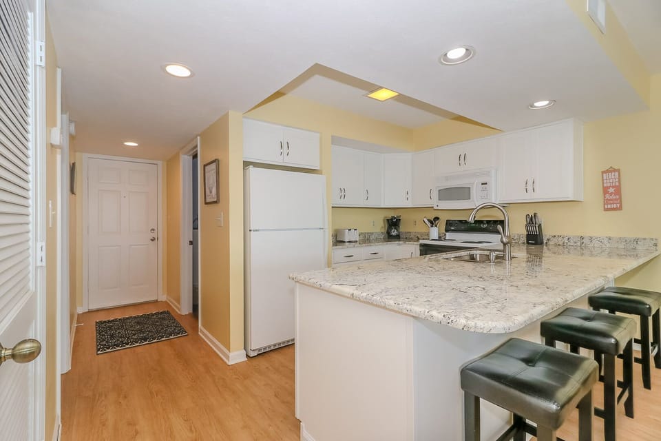 Your fully equipped kitchen features granite counters, white cabinets, and a breakfast bar where you can enjoy morning coffee.