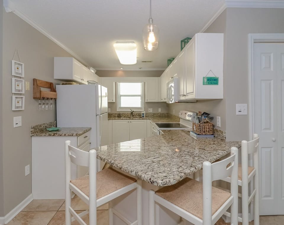 Your fully equipped kitchen features granite counters and breakfast bar seating, perfect for preparing meals and casual dining together.
