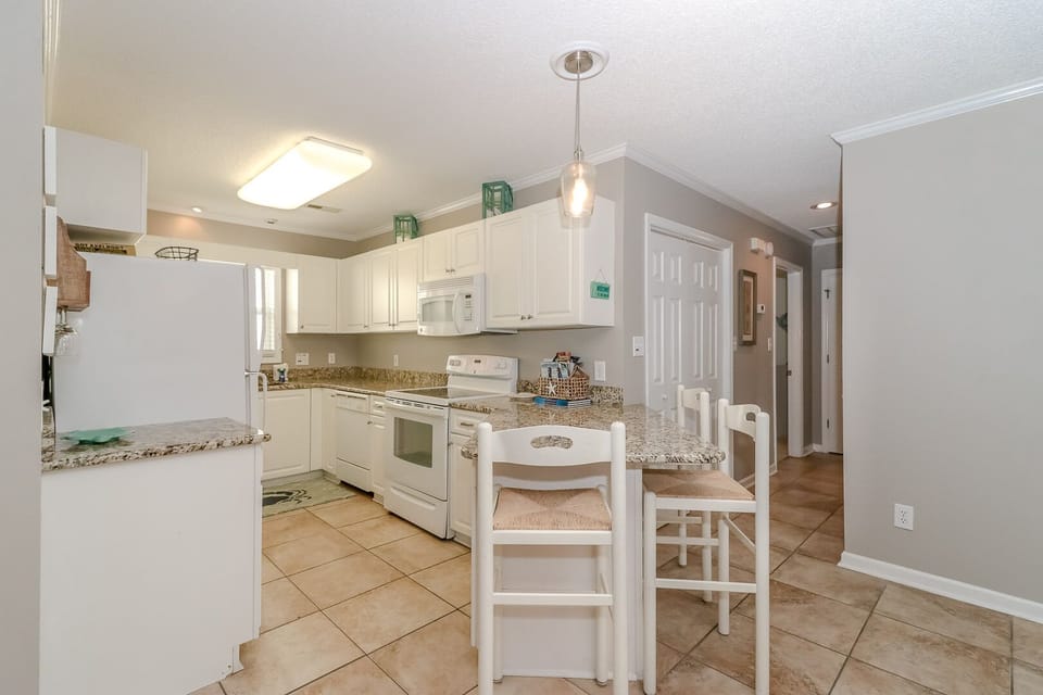 Your fully equipped kitchen features granite counters and breakfast bar seating, perfect for preparing meals and casual dining together.
