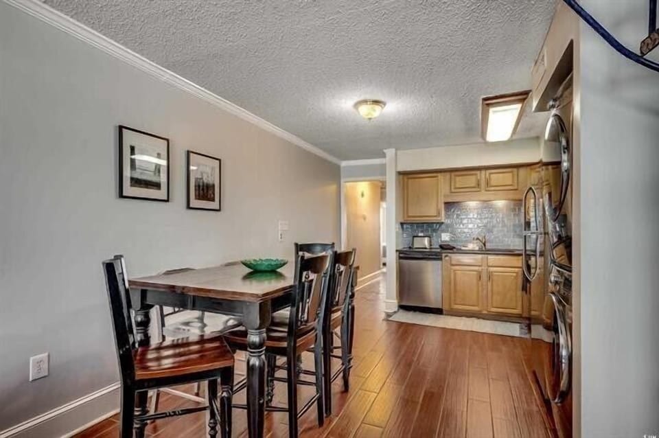 Step into your stylish open-concept living space where warm hardwood floors flow from dining to kitchen, creating perfect harmony for meals together.