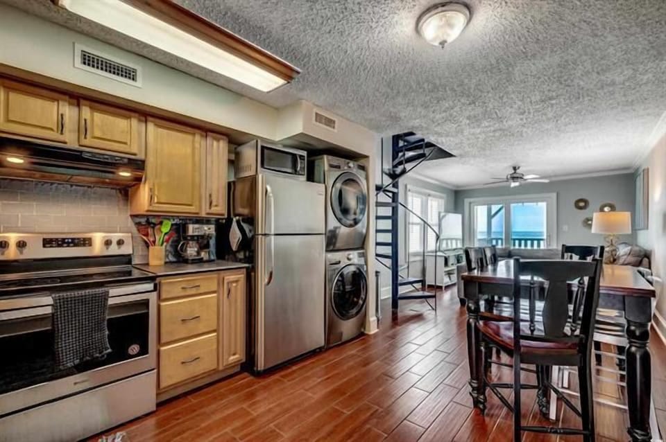 Your modern kitchen features stainless steel appliances and in-unit laundry, with warm hardwood floors leading to your dining area and ocean views.