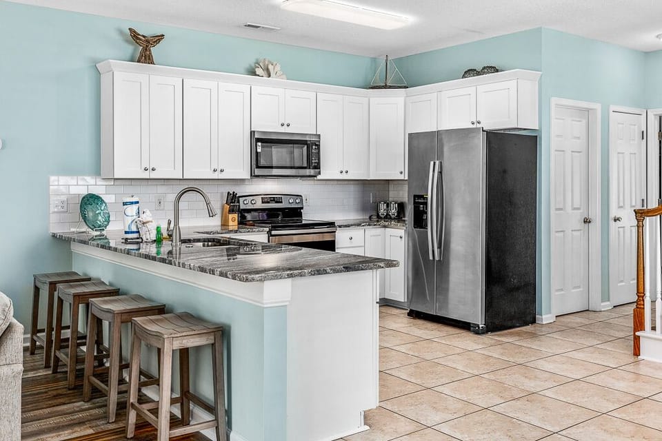 Your fully equipped kitchen features granite countertops, stainless steel appliances, and a breakfast bar where you can sip morning coffee overlooking coastal-themed décor.