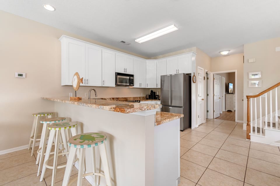 Cook meals together in your spacious kitchen featuring granite countertops, stainless steel appliances, and a cheerful breakfast bar.