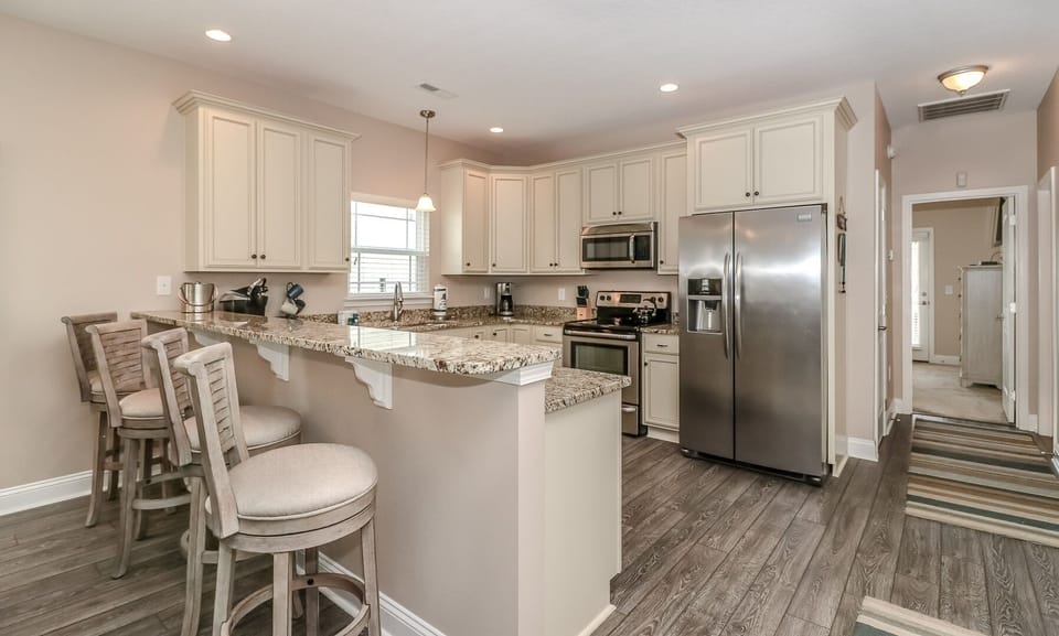 Your fully equipped kitchen features granite countertops, stainless steel appliances, and a breakfast bar perfect for morning coffee and casual meals.