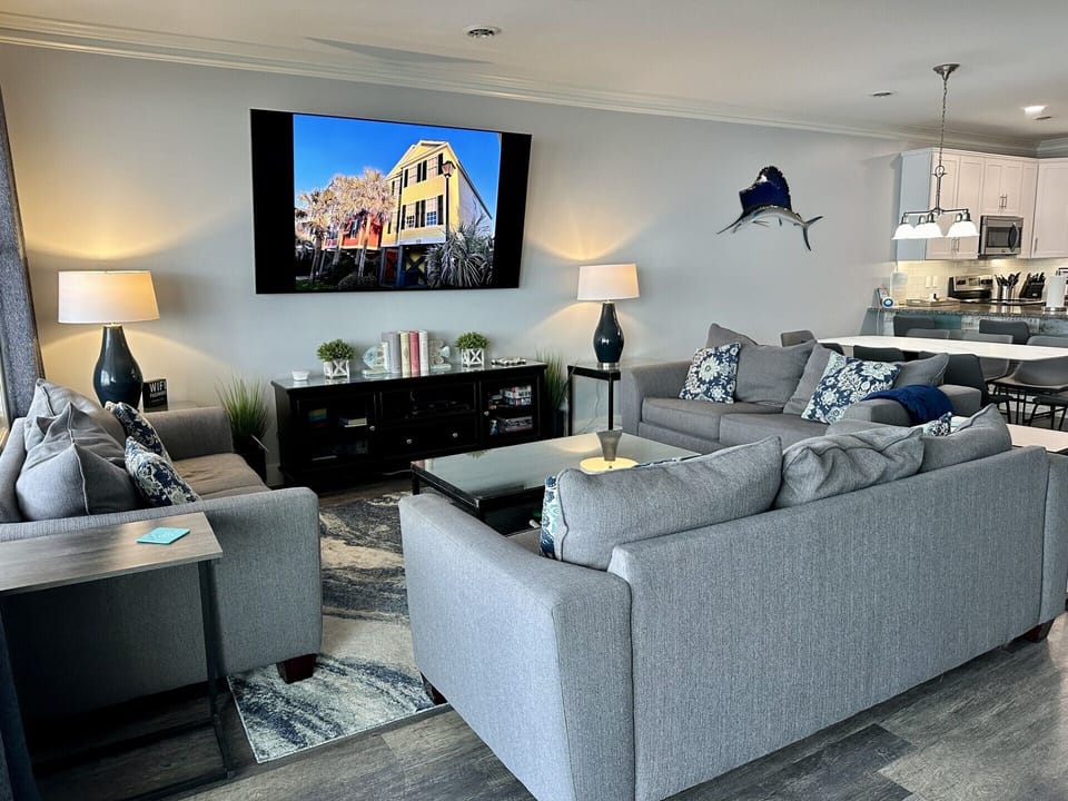 Unwind in your spacious living room featuring plush sectional seating, large smart TV, and open kitchen perfect for entertaining.