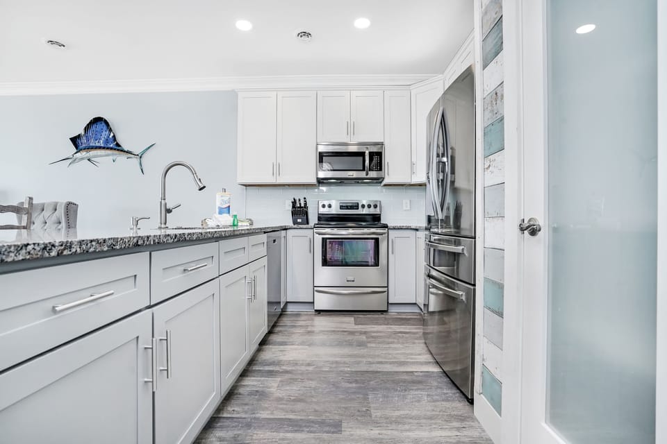 Your fully equipped kitchen awaits with granite counters, stainless appliances, and coastal charm to inspire memorable meals together.