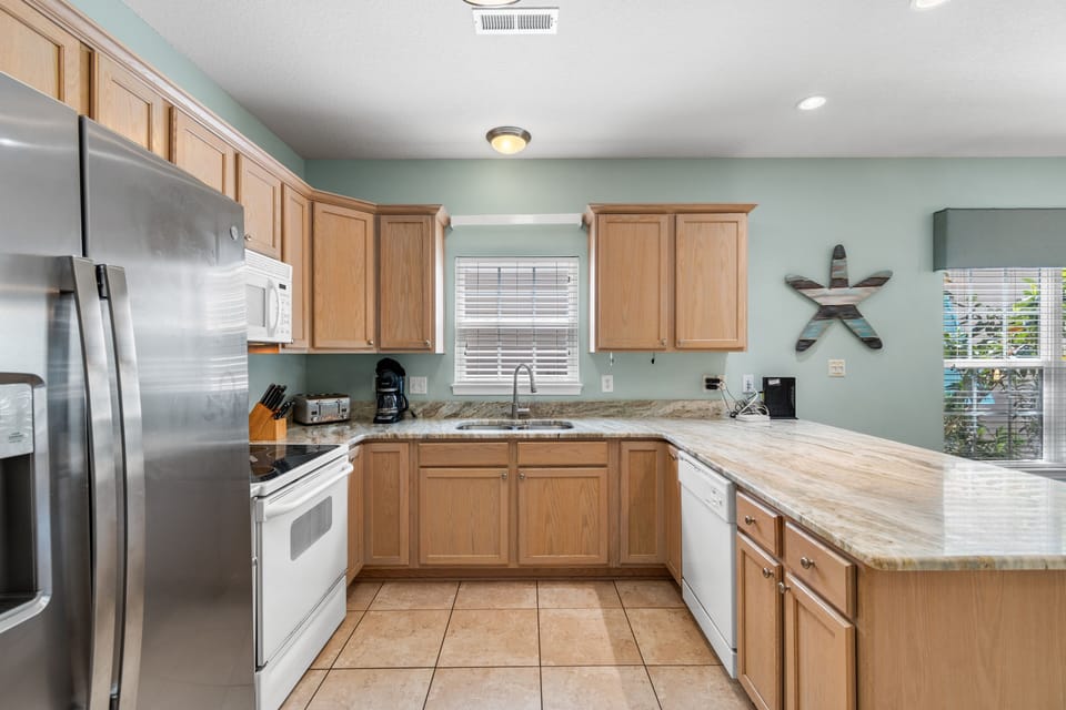 Your fully equipped kitchen features granite counters, stainless appliances, and coastal decor for memorable meal prep.