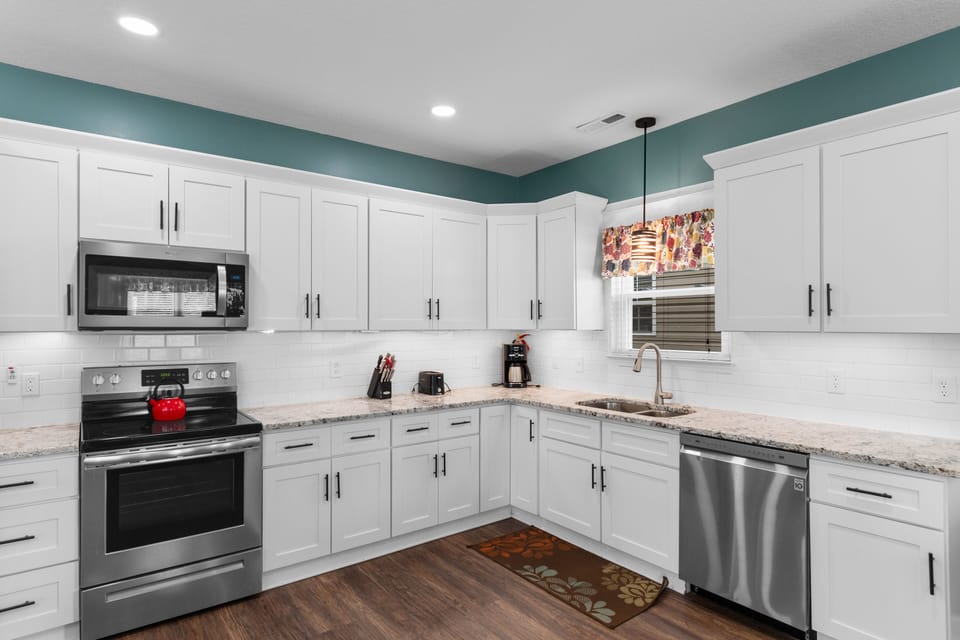 Your fully equipped kitchen awaits with pristine white cabinetry, granite countertops, and modern stainless steel appliances for memorable home-cooked meals.