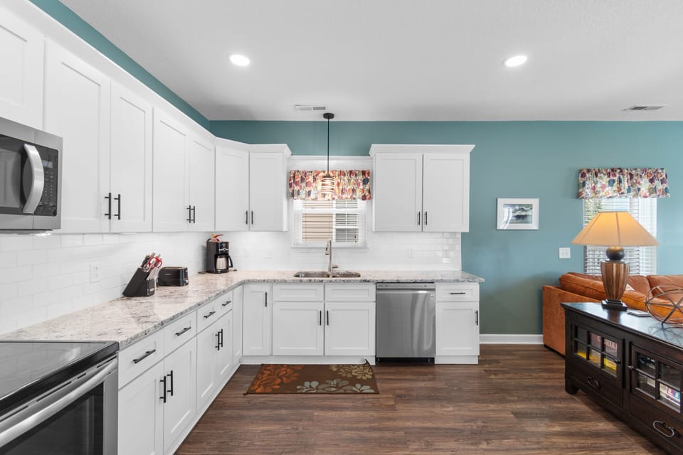 Your fully equipped kitchen awaits with granite counters, stainless appliances, and cheerful turquoise accents for memorable meal prep.
