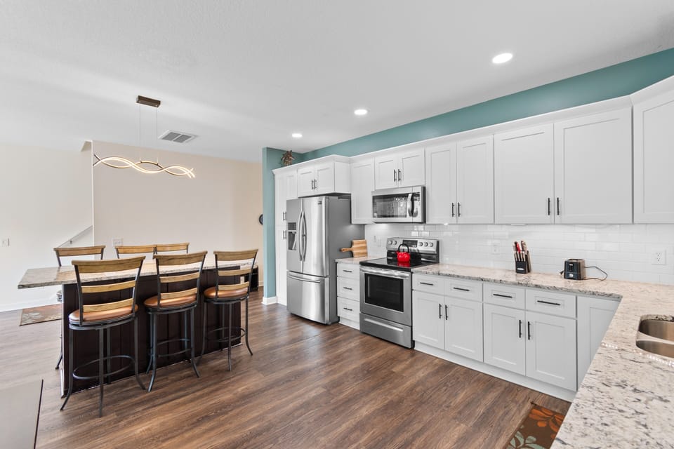 Your fully equipped kitchen sparkles with granite counters, stainless appliances, and a breakfast bar perfect for morning coffee together.