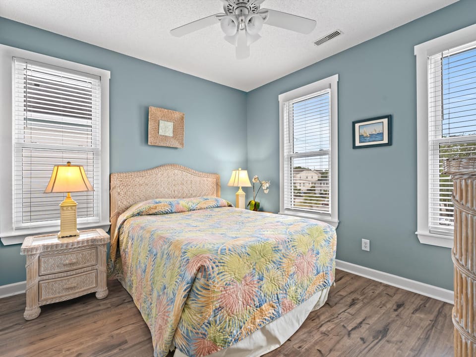 Drift off in your tropical-themed bedroom with coastal blue walls, ceiling fan, and colorful bedding that captures island vibes.