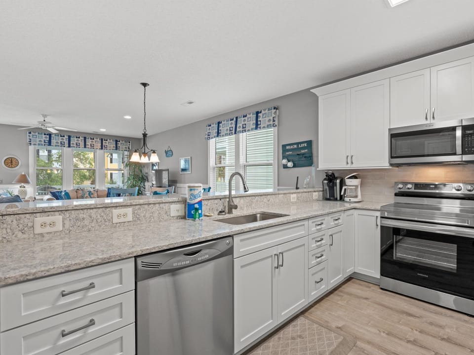 Cook memorable meals in your fully-equipped kitchen with granite counters, stainless appliances, and natural light streaming through cheerful blue valances.