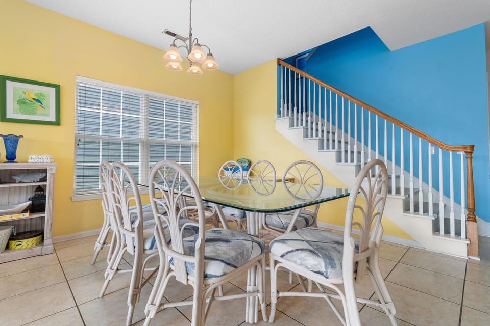 Gather around your sunny dining table, where vibrant yellow walls and cheerful coastal decor create the perfect backdrop for memorable meals together.