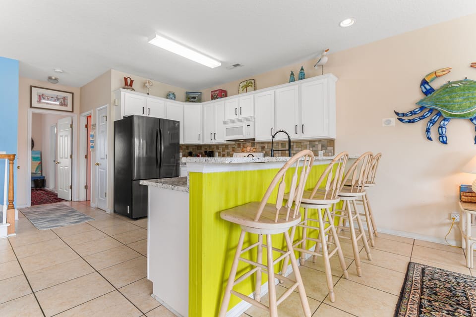 Your bright kitchen features white cabinets, granite counters, and a vibrant lime green island with bar seating for casual meals.