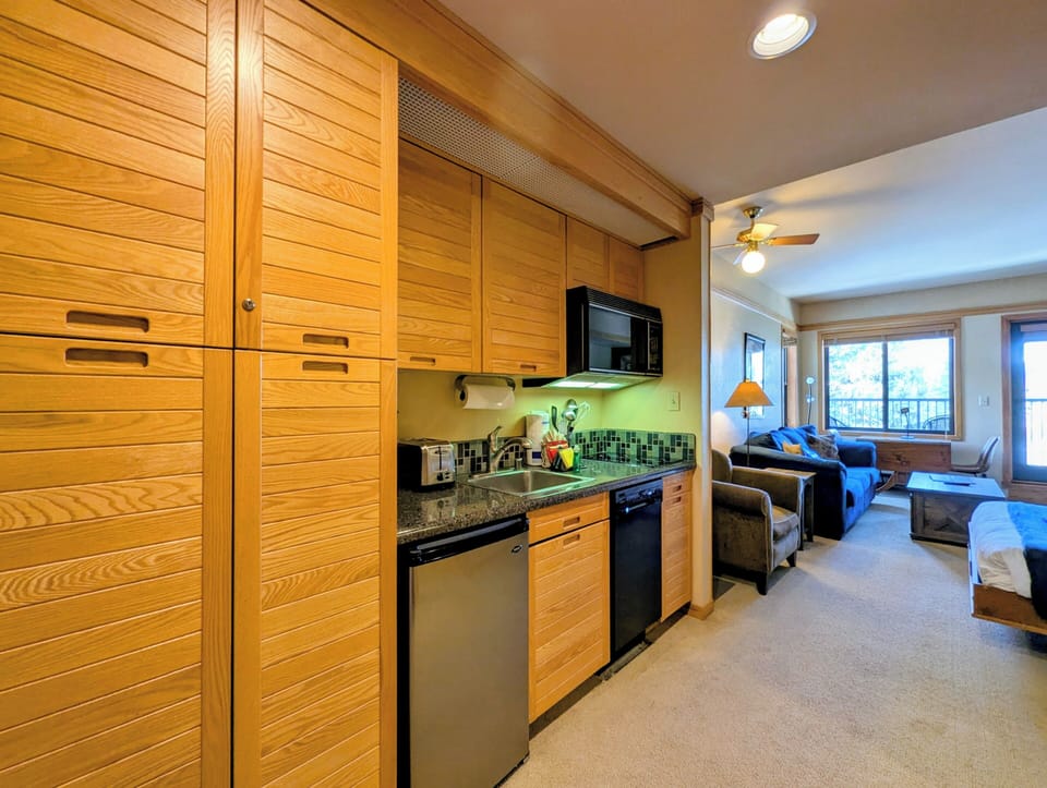 Step into your stylish retreat where warm wood cabinetry and granite countertops create a seamless kitchen-living space perfect for relaxing.