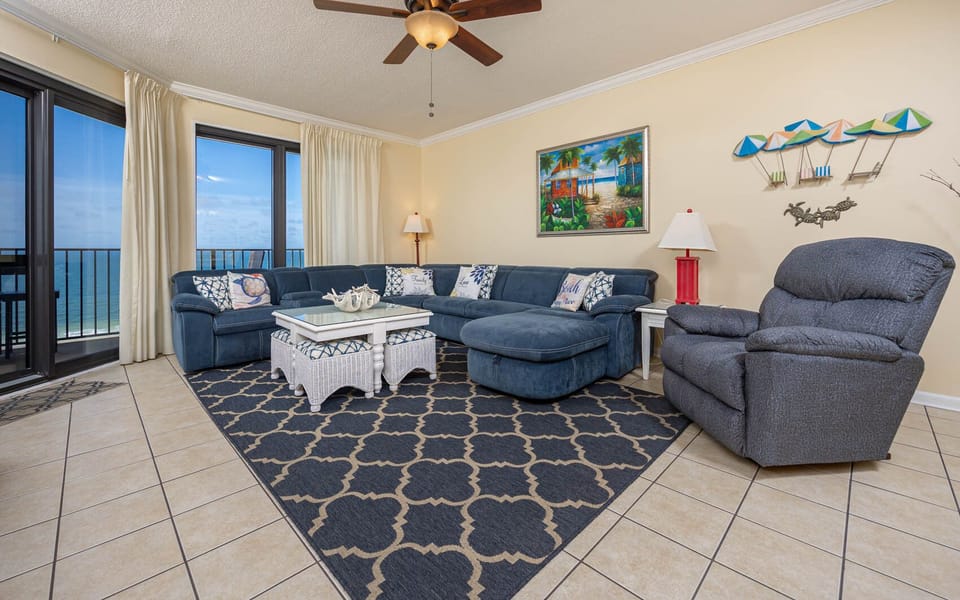 Cozy living area features a large blue sectional sofa with queen sleeper, decorative pillows, and a vibrant beach painting