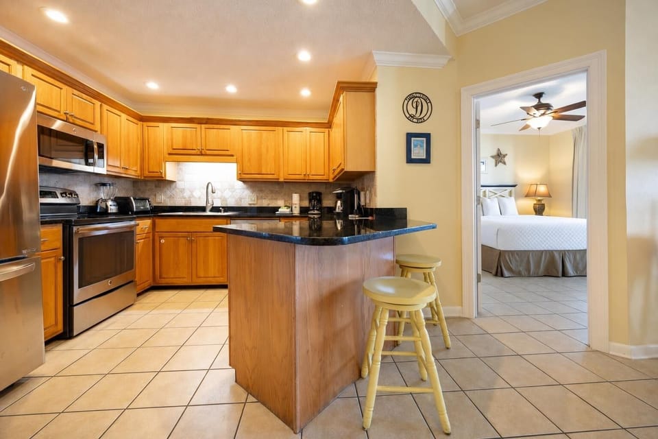 Warm wooden cabinetry complements the modern kitchen with a breakfast bar and coffee station