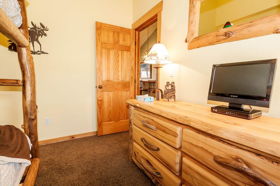Cozy rustic bedroom with handcrafted log furniture, flat-screen TV, and charming woodland décor for your mountain retreat.