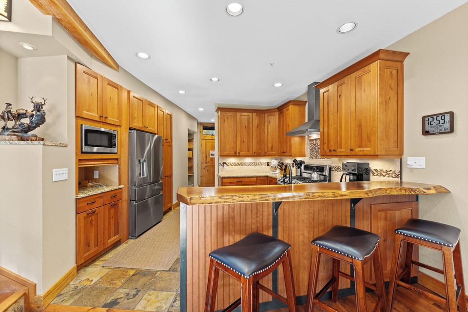 Your fully-equipped gourmet kitchen features warm wood cabinetry, granite countertops, and a breakfast bar where you'll love gathering for morning coffee.