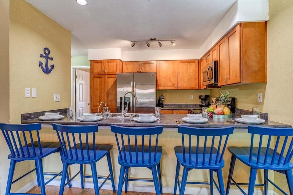 Spacious kitchen with a wide breakfast counter, wood cabinetry, and stainless appliances for easy vacation cooking.